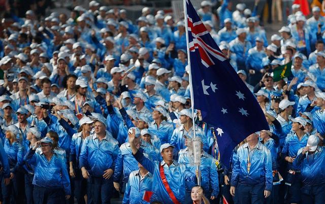 James Tomkins of the Australia Olympic rowing team carries his country's flag to lead out the.jpg