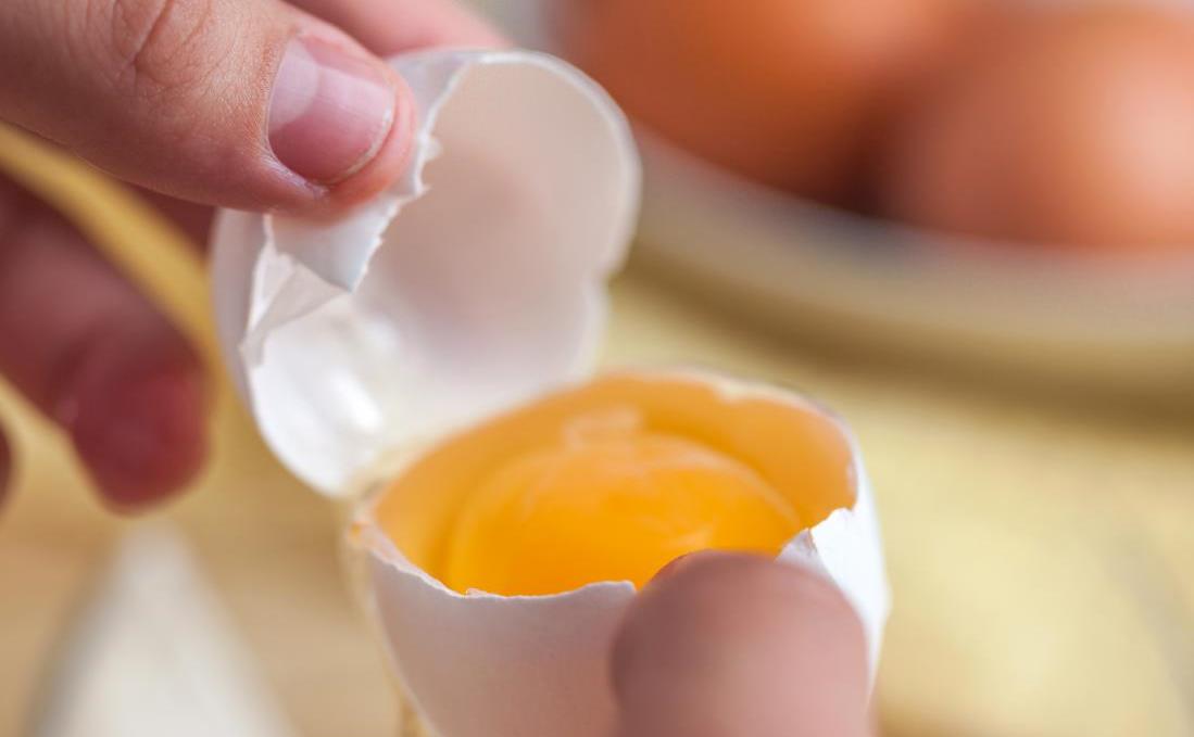 a-hand-holding-a-cracked-egg-showing-a-yolk.jpg